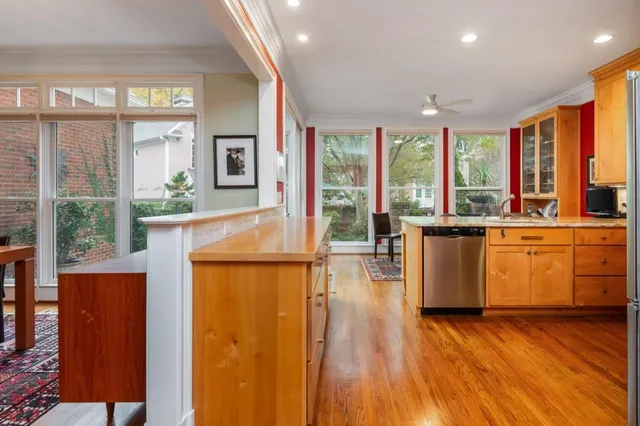 a view of a kitchen with kitchen island a large window cabinets a sink and stainless steel appliances