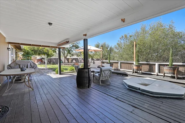 a view of a patio with lawn chairs wooden floor and floor to ceiling window