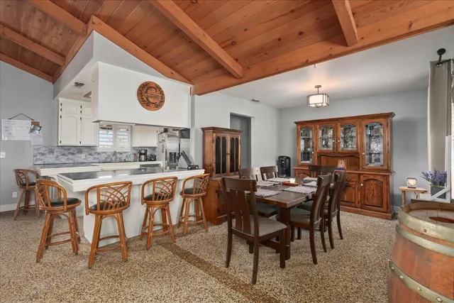 a dining hall with stainless steel appliances granite countertop a stove a sink a dining table and chairs with wooden floor