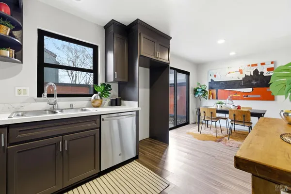 a kitchen with stainless steel appliances granite countertop a refrigerator a sink dishwasher a dining table and chairs with wooden floor