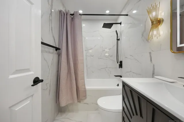 a bathroom with a sink a toilet a mirror and shower