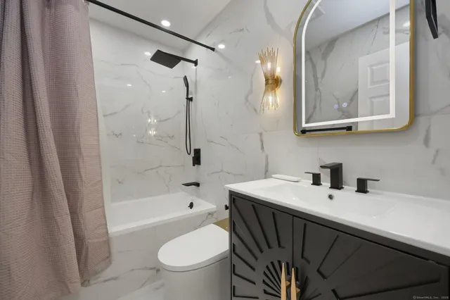 a bathroom with a sink a toilet a mirror a vanity and bathtub