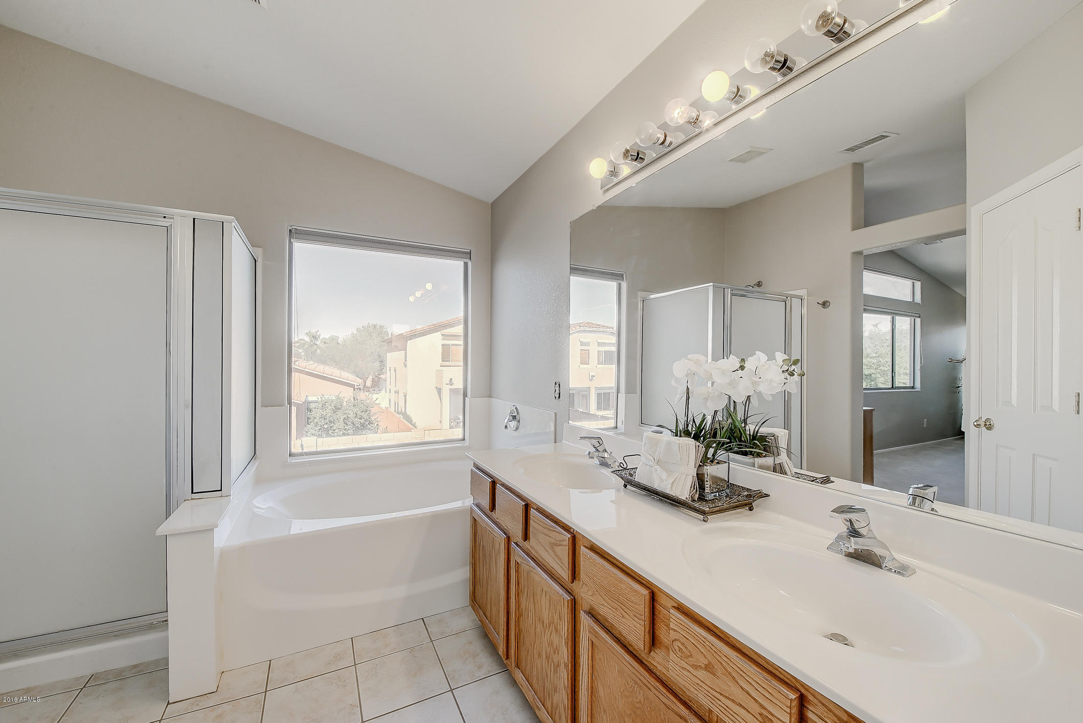 4016 East Ironhorse Road Gilbert, AZ 85297 - Photo 31 of 48 a bathroom with double vanity sinks a large mirror and a bathtub