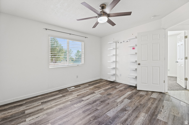 5525 Hampton Way Stansbury Park, UT 84074 - Photo 16 of 35 Spacious room featuring wood-finish flooring, a ceiling fan with integrated lighting, built-in shelving, and a window with horizontal blinds