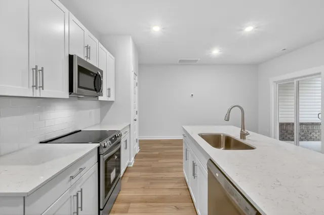 a kitchen with stainless steel appliances granite countertop a sink and a stove top oven with wooden floor