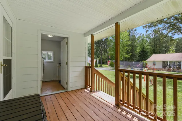 a balcony with wooden floor outdoor seating and yard in the back