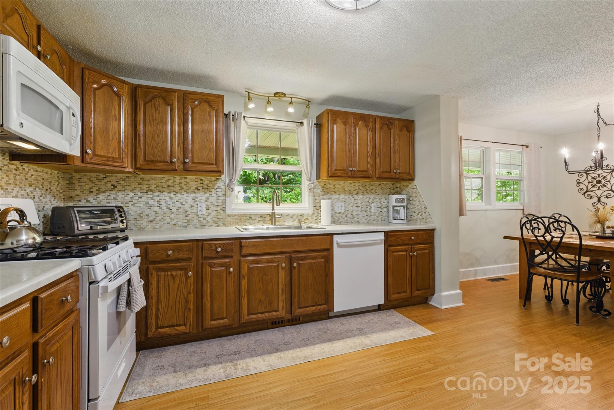 4230 Train Chaser Place Fort Mill, SC 29707 - Photo 4 of 31 a kitchen with stainless steel appliances granite countertop wooden cabinets a sink a stove a dining table and chairs