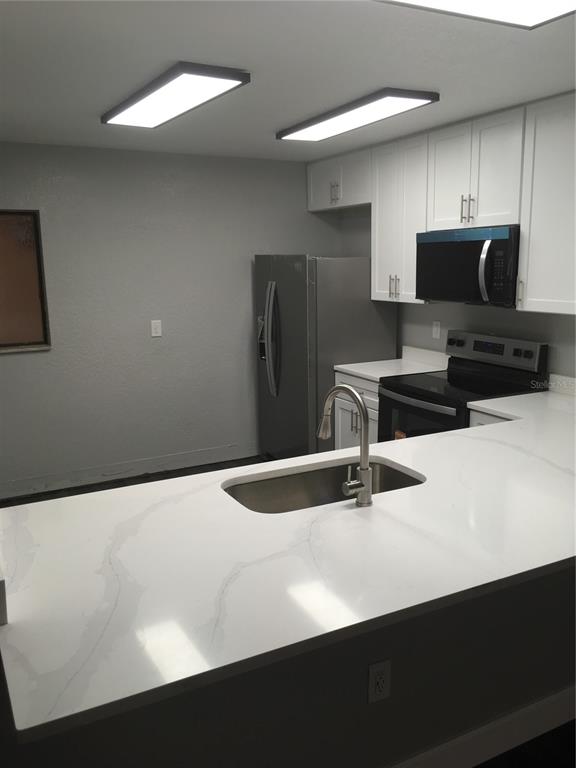 630 Cranes Way, Unit 307 Altamonte Springs, FL 32701 - Photo 2 of 8 a kitchen with stainless steel appliances a sink a microwave a refrigerator and white cabinets