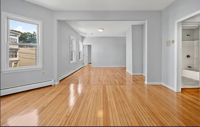a view of wooden floor in an empty room with a window