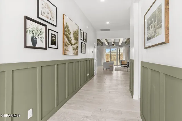 a hallway with painting on the wall and a large window