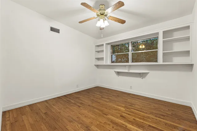 an empty room with a window and a fan