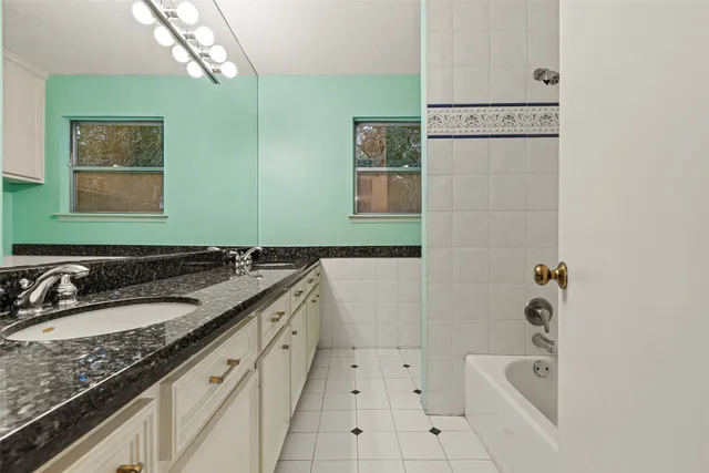 a bathroom with a granite countertop sink mirror and bathtub