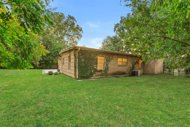 a backyard of a house with large trees and plants