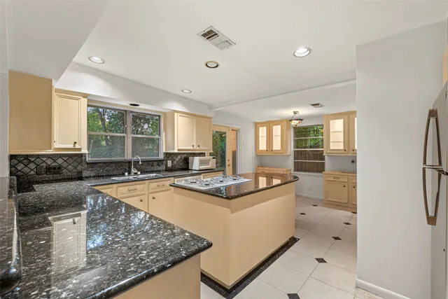 a kitchen with stainless steel appliances granite countertop a sink and a refrigerator
