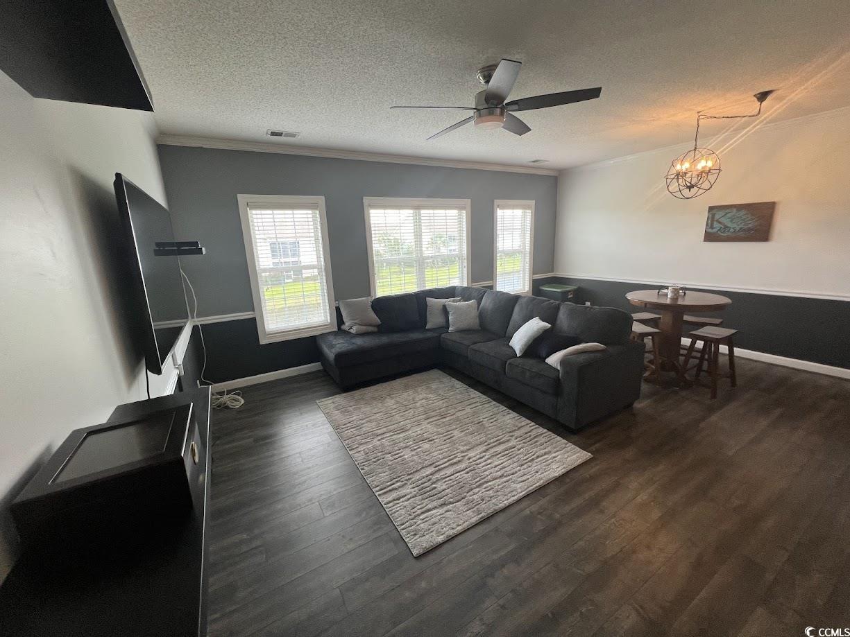 3965 Forsythia Court, Unit 202 Myrtle Beach, SC 29588 - Photo 6 of 15 Living area featuring ceiling fan, a textured ceiling, ornamental molding, dark wood-style floors, and a chandelier