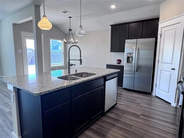 a kitchen with stainless steel appliances granite countertop a sink a stove and a refrigerator