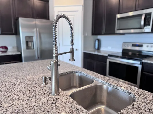 a kitchen with stainless steel appliances kitchen island granite countertop a stove a sink and a refrigerator