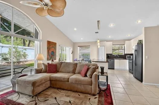 a living room with furniture kitchen view and a large window