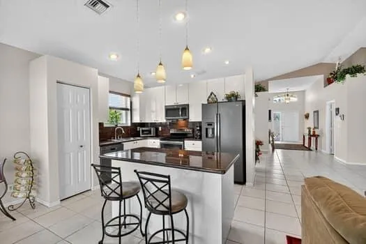 a kitchen with stainless steel appliances kitchen island granite countertop a refrigerator and microwave