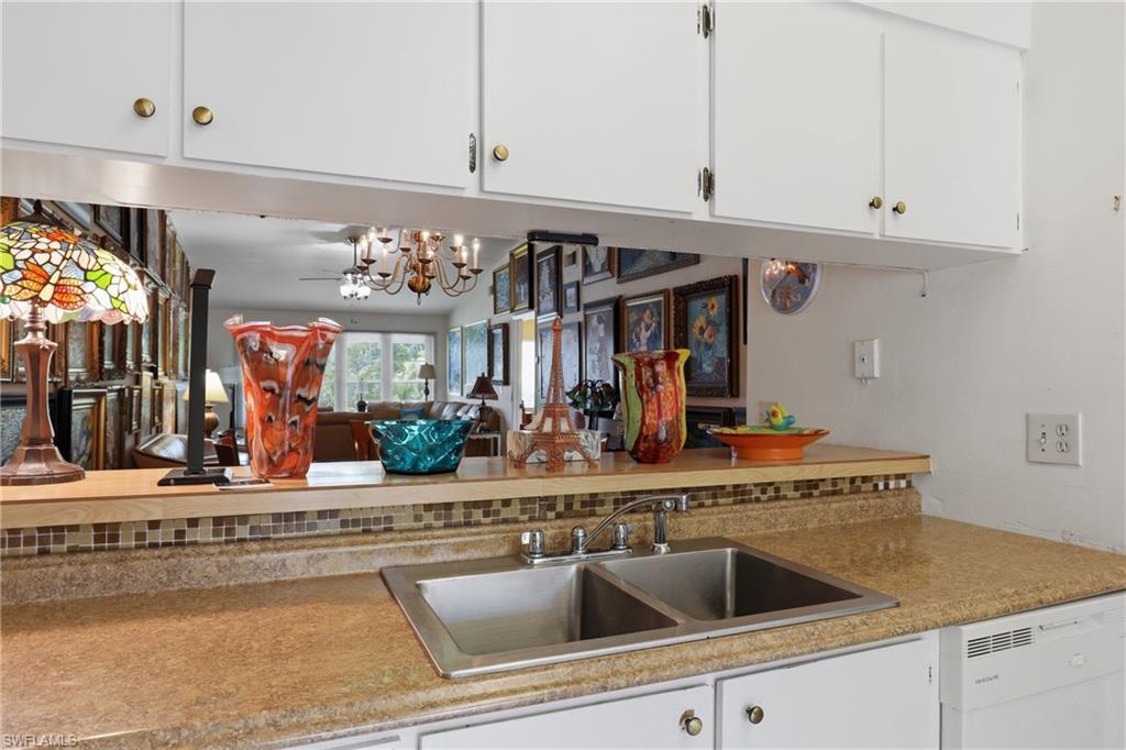 4050 Ice Castle Way, Unit 2812 Naples, FL 34112 - Photo 11 of 49 Kitchen area featuring a stainless steel double-basin sink, laminate countertops, and a mosaic tile backsplash