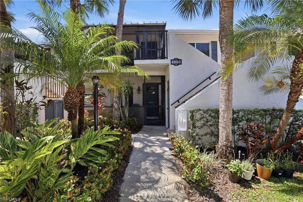 4050 Ice Castle Way, Unit 2812 Naples, FL 34112 - Photo 2 of 49 White stucco exterior featuring a private entrance, exterior staircase with dark handrail, and a second-story balcony with dark railings