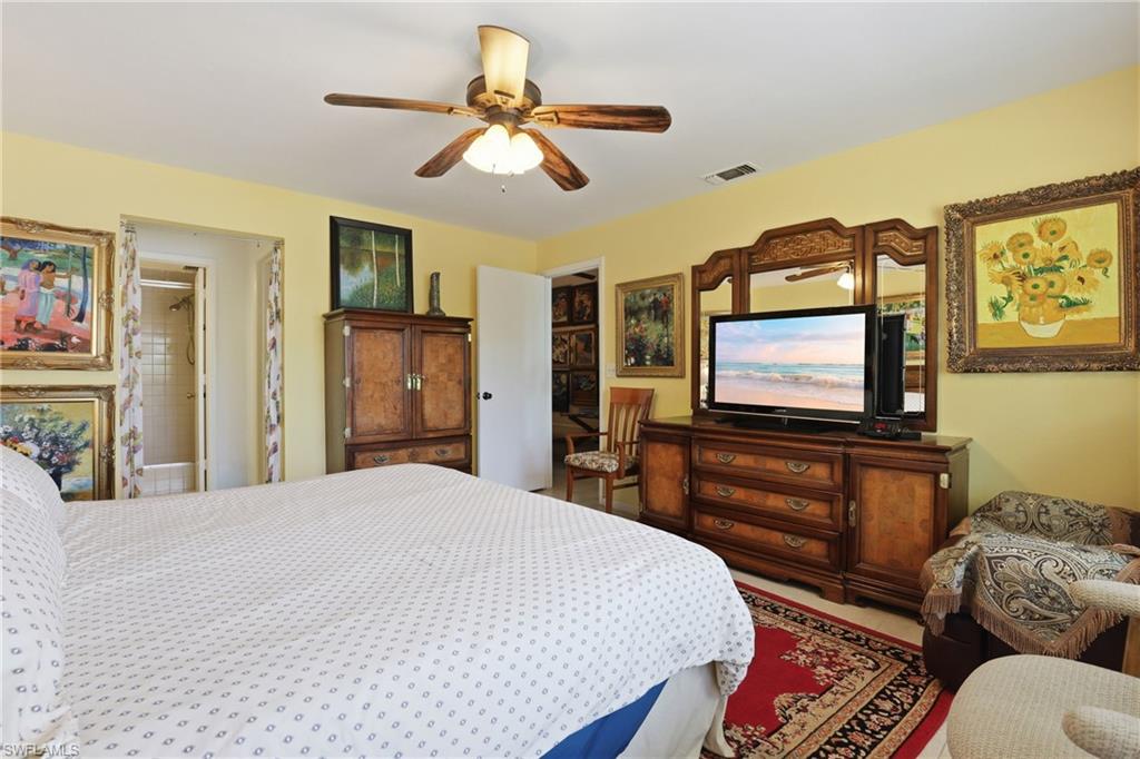 4050 Ice Castle Way, Unit 2812 Naples, FL 34112 - Photo 29 of 49 Spacious room featuring a ceiling fan with light fixture, light yellow wall color, and a partial view of a bathroom with a tiled shower