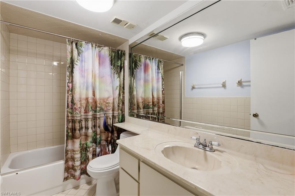 4050 Ice Castle Way, Unit 2812 Naples, FL 34112 - Photo 36 of 49 Bathroom featuring a large vanity with an integrated sink, an expansive wall-mounted mirror, a toilet, and a combination shower/bathtub with tile surround