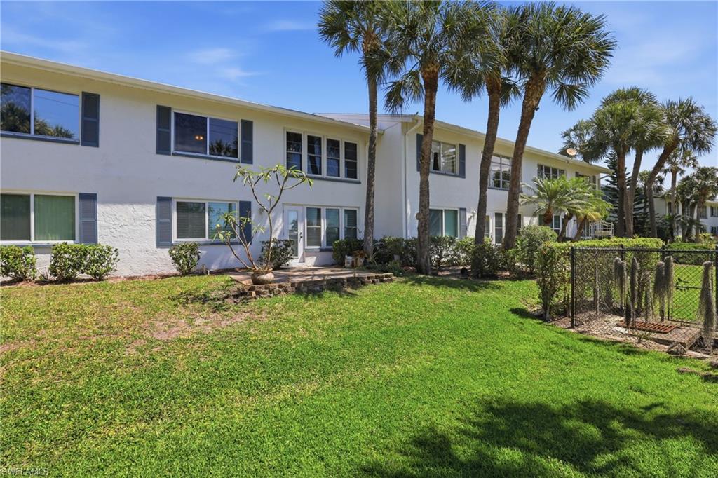 4050 Ice Castle Way, Unit 2812 Naples, FL 34112 - Photo 40 of 49 Two-story stucco building with multiple windows, framed by mature palm trees and lush green lawn