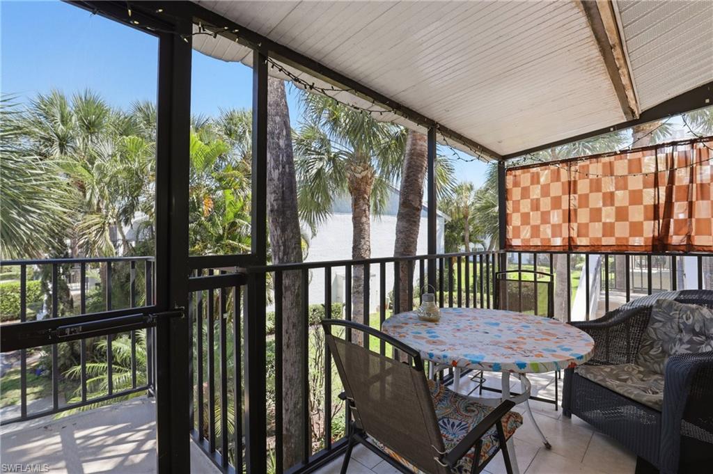 4050 Ice Castle Way, Unit 2812 Naples, FL 34112 - Photo 4 of 49 Screened balcony featuring a white corrugated ceiling, dark metal railings, and a partial privacy screen