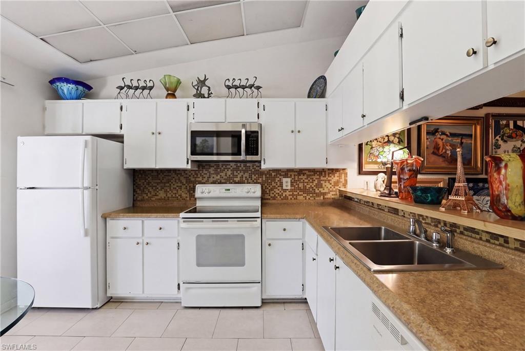 4050 Ice Castle Way, Unit 2812 Naples, FL 34112 - Photo 8 of 49 Kitchen featuring white cabinetry, stainless steel sink, built-in microwave, and tile flooring