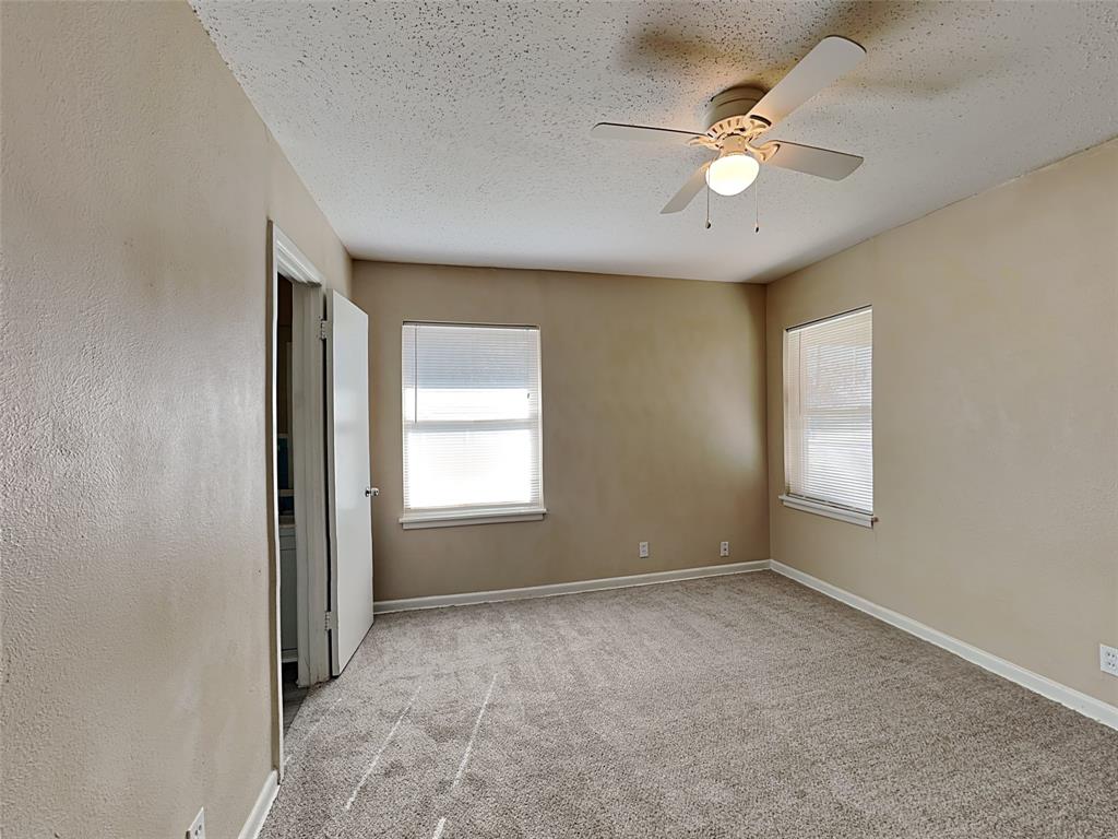 649 West Main Street Lancaster, TX 75146 - Photo 7 of 14 Empty room with light carpet, a textured ceiling, a textured wall, and a ceiling fan