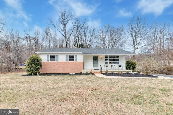 a front view of house with yard and trees in the background