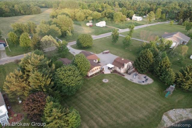 5461 North Henderson Road Davison, MI 48423 - Photo 8 of 64 Expansive property featuring a large manicured lawn, established landscaping, a spacious patio, a defined fire pit area, and a private pond