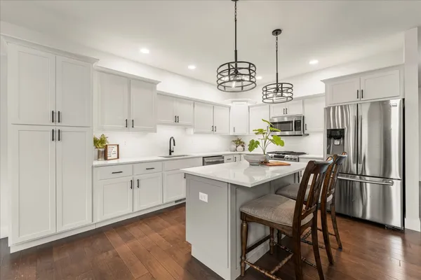 a kitchen with kitchen island granite countertop a sink a counter space appliances and cabinets