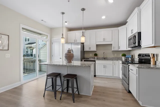 a kitchen with stainless steel appliances granite countertop a table chairs refrigerator and microwave