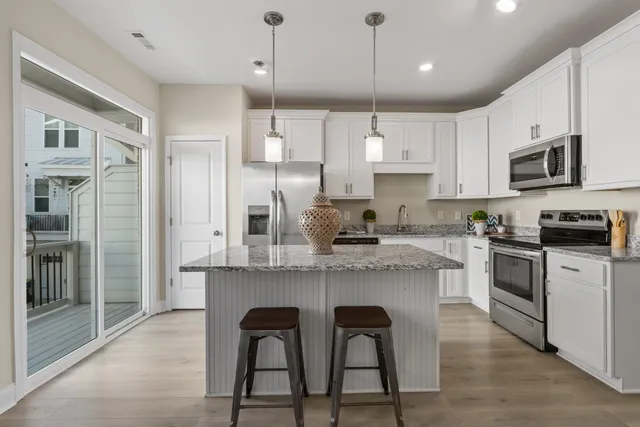 a kitchen with kitchen island white cabinets and stainless steel appliances