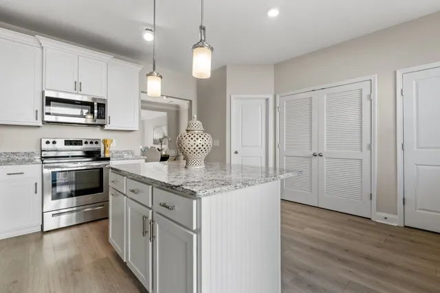 a kitchen with stainless steel appliances granite countertop a sink stove and white cabinets