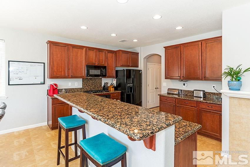 11190 Messina Way Reno, NV 89521 - Photo 8 of 21 a kitchen with stainless steel appliances granite countertop a stove top oven a sink dishwasher and a refrigerator with wooden cabinets