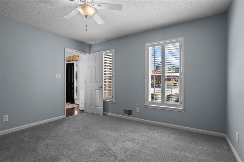 4350 Fallowfield Lane Southwest Lilburn, GA 30047 - Photo 17 of 64 an empty room with chandelier fan and windows