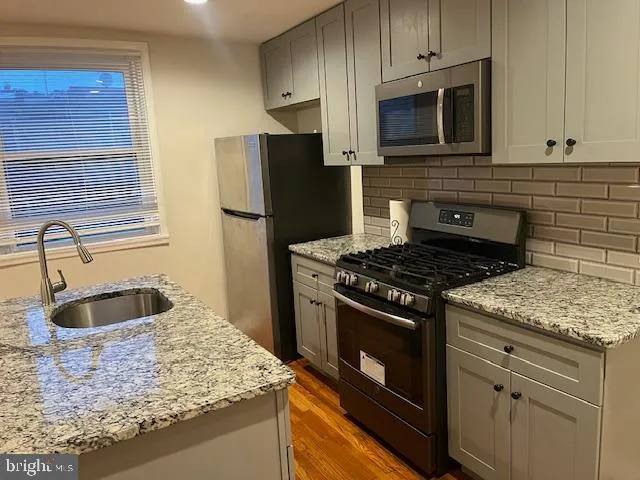 a kitchen with granite countertop a sink stainless steel appliances and cabinets