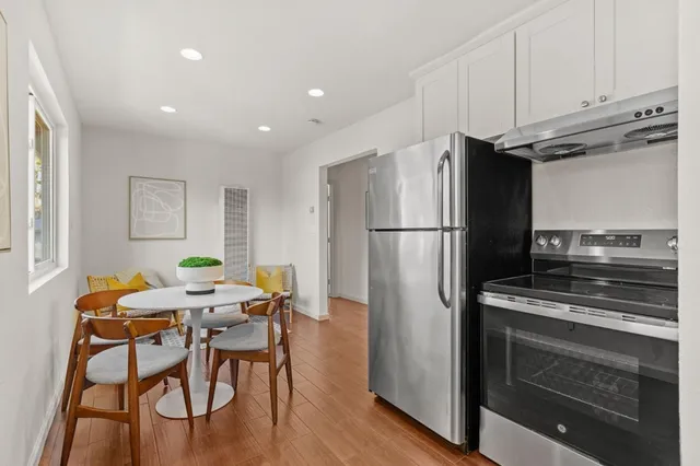 a kitchen with stainless steel appliances a refrigerator a stove a dining table and chairs