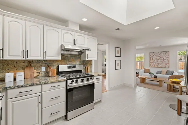 a kitchen with stainless steel appliances granite countertop a stove and white cabinets