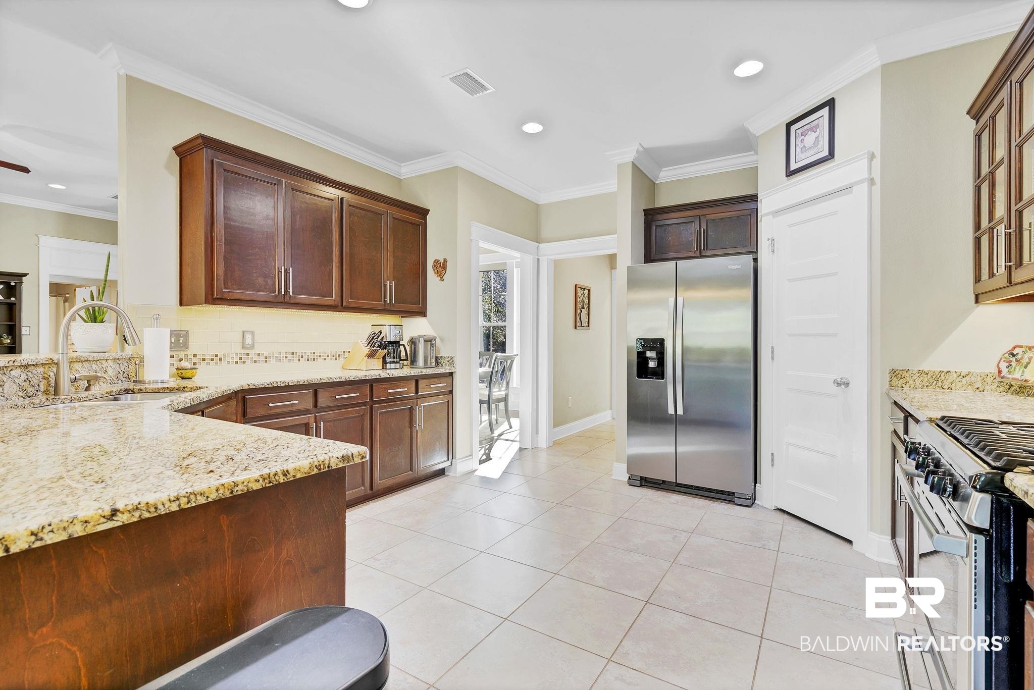 20105 Bunker Loop Fairhope, AL 36532 - Photo 22 of 65 Kitchen with visible vents, ornamental molding, a sink, light stone counters, and stainless steel appliances