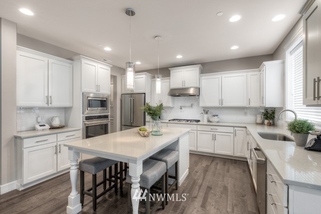 23226 7th Drive Southeast Bothell, WA 98021 - Photo 9 of 24 a kitchen with a sink a stove a refrigerator and white cabinets with wooden floor