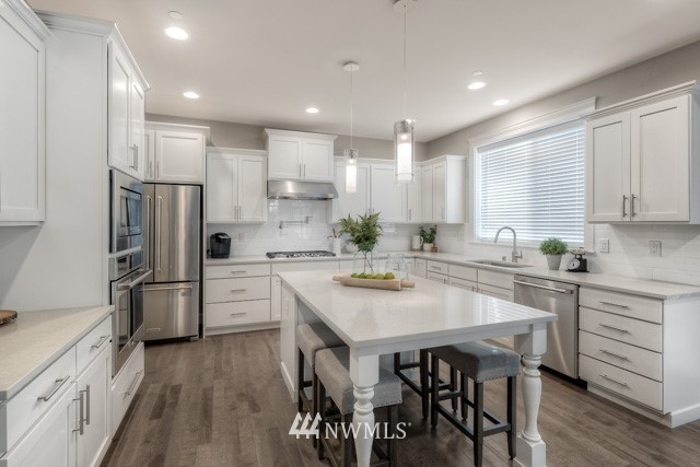 23226 7th Drive Southeast Bothell, WA 98021 - Photo 10 of 24 a kitchen with a sink a stove a refrigerator and white cabinets with wooden floor