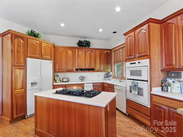 a kitchen with stainless steel appliances a refrigerator a sink a stove and white cabinets