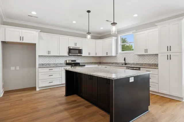 a kitchen with kitchen island granite countertop a sink a stove and a refrigerator