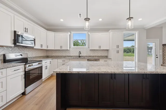 a kitchen with granite countertop a sink cabinets and stainless steel appliances