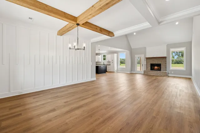 an empty room with wooden floor fireplace and windows
