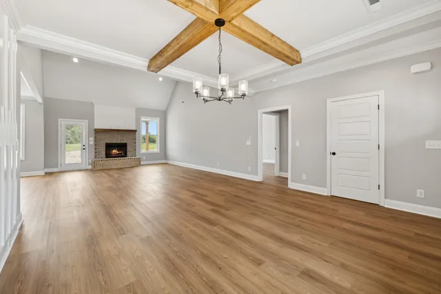 an empty room with wooden floor chandelier fan and windows